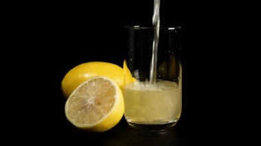 Siyah arka plan cam içine taze limon suyu dökülür