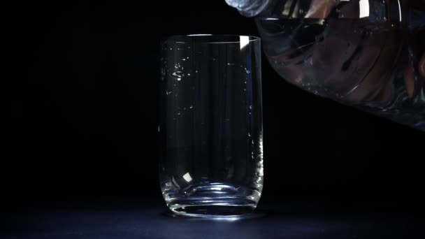 Un verre d'eau est versé d'une bouteille en plastique dans un verre 
