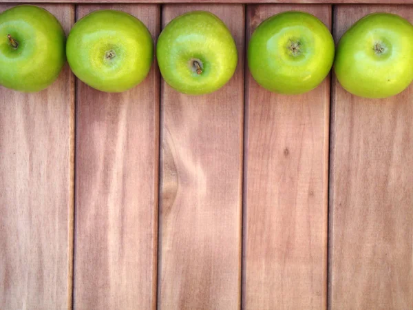green apples and herbs leaves on wooden background from boards of a background for the label