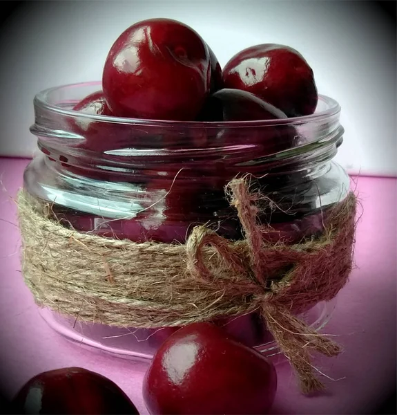 red sweet cherry. sweet cherry in bank on a pink background. free space.