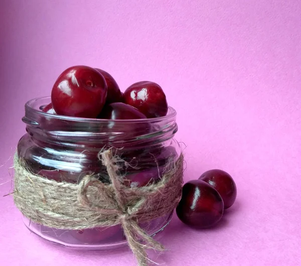 red sweet cherry. sweet cherry in bank on a pink background. free space.