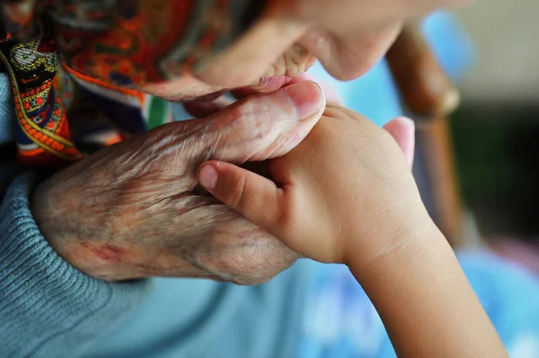 Uma mulher idosa beijando as mãos das crianças. Passeio de verão na rua. 1 ano e 90 anos . — Fotografia de Stock