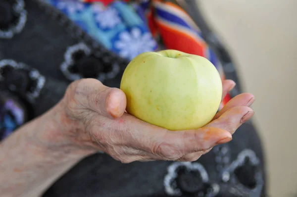 成熟的苹果在一个穿着针织背心的老太太手里散步 90年了健康和营养 复制空间 — 图库照片