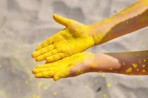 Nahaufnahme von oben von leeren niedlichen Kinderhänden, die sich durch buntes Puder schmutzig machen. Gelbe Farbholi am Strand. — Stockfoto