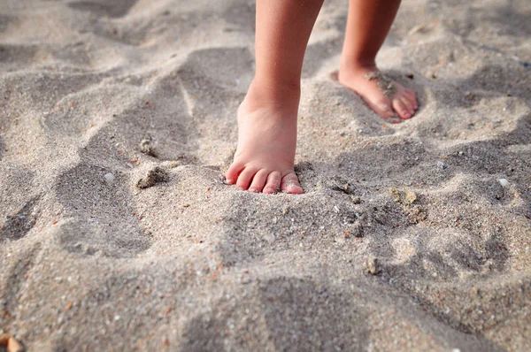 Μικρά παιδικά πόδια πάνω στην αμμώδη παραλία το καλοκαίρι. — Φωτογραφία Αρχείου