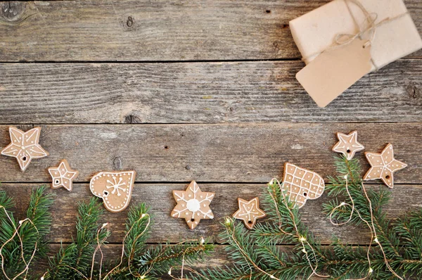 Merry christmas holiday decoratie achtergrond. Traditionele zelfgemaakte Christmas peperkoek suiker glazuur en gift box op een houten achtergrond. Kerstboom versierd met lichten. Kopiëren van ruimte — Stockfoto