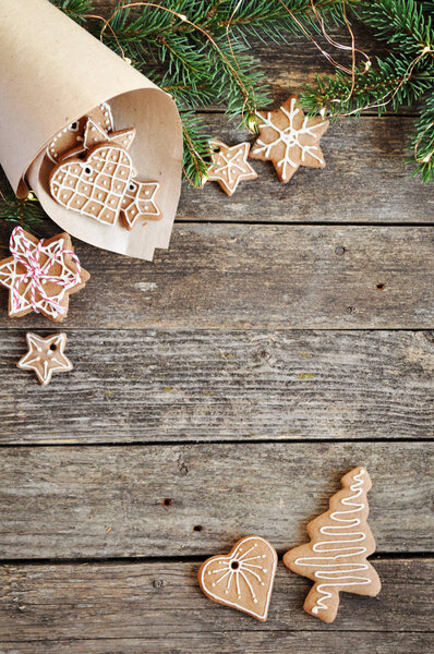 Merry christmas holiday decoration background. Traditional homemade Christmas gingerbread sugar frosting in paper envelope on wooden background. Christmas tree decorated with lights. Save space