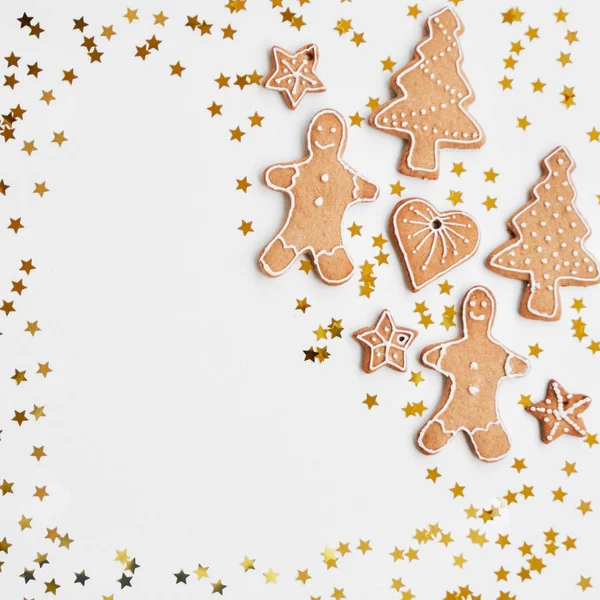 Vacanza sfondo lucido. Biscotti di pan di zenzero fatti in casa tradizionali glassa di zucchero a forma di ometto divertente, stelle, cuori, albero e bullone d'oro su uno sfondo bianco. Ornamenti natalizi . — Foto Stock