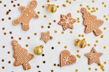 Tatil parlak arka plan. Geleneksel ev yapımı gingerbread çerezleri beyaz zemin üzerinde bir komik küçük adam, yıldız, kalp, ağaç, Altın Koza şeklinde buzlanma şeker. Noel süsler. üstten görünüm