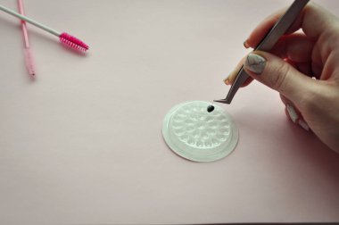 Kirpik uzatma yordamı. Kadın elle Closeup kirpik uzatma için aracı. Cımbız üstadı çalışıyor.