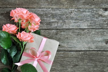 Hassas mercan pembe gül ve hediye rustik ahşap zemin üzerine gölge. Sevgiliye arka plan. Tatil kartı kadınlar için