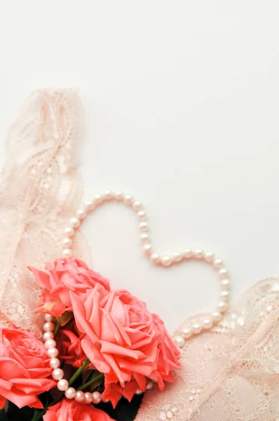 Zartes feminines Thema. rosa Korallenrosen Trendfarbe auf blassrosa BH und Perlenkette auf weißem Hintergrund. Ansicht von oben. Nahaufnahme. stilvolle Dessous flach lag. Unterwäsche Modekonzept — Stockfoto