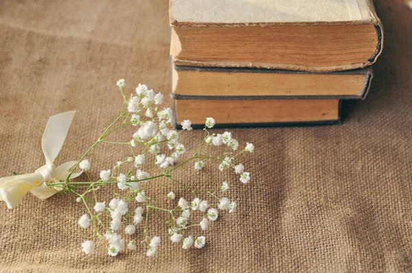 Vintage spring background with white flowers, a yellowed old books on the burlap. closeup. — Stock Photo, Image