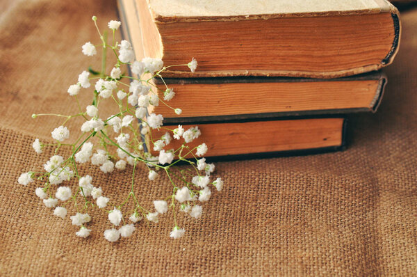 Vintage spring background with white flowers, a yellowed old books on the burlap. closeup. toned