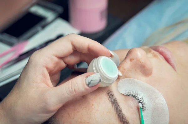 Eyelash Extension Procedure. Woman hands Closeup with tool to remove lashes. Master of tweezers is working.