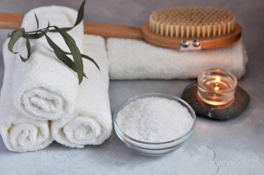 Spa görünümü kadar yakın kavramı sakin ol. Beyaz Terry havlu, taşlar, mum, deniz tuzu ve ahşap masaj fırça dokulu gri bir arka plan üzerinde.
