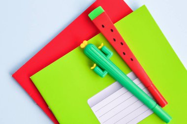 Mavi arka planda bir kaktüs, karpuz ve renkli notebooklar şeklinde parlak Kırtasiye Kalemler. Okula dönüyoruz. Üst görünüm.