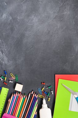 Siyah bir Tahta arka plan defterleri, kalemler, makas ve diğerleri parlak kırtasiye. Kavram okula geri