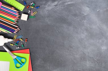 Siyah bir Tahta arka plan defterleri, kalemler, makas ve diğerleri parlak kırtasiye. Kavram okula geri