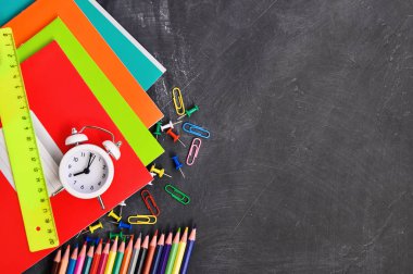 Siyah tahta arka plan defterleri, kalemler, makas ve diğerleri parlak kırtasiye.