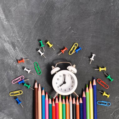 Çalar saat, siyah okul Kurulu arka planda renkli kalemler ve kırtasiye