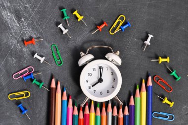 Çalar saat, siyah okul Kurulu arka planda renkli kalemler ve kırtasiye