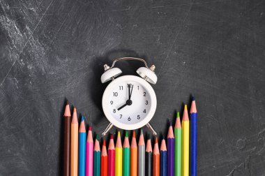 Çalar saat, siyah okul Kurulu arka planda renkli kalemler ve kırtasiye