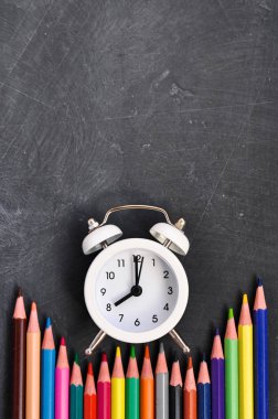 Çalar saat, siyah okul Kurulu arka planda renkli kalemler ve kırtasiye