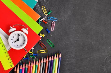 Siyah tahta arka plan defterleri, kalemler, makas ve diğerleri parlak kırtasiye.