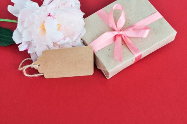 Pembe şakayık çiçek kırmızı arka plan üzerinde hediye kutusu yanında.