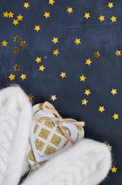 Rahat büyülü beyaz örme eldivenler karanlık bir arka plan üzerinde parlak bir kalp tutmak.