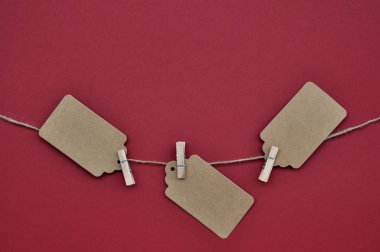 Kağıt zanaat indirim etiketleri kırmızı bir arka plan üzerinde halat clothespins ile eklenir.