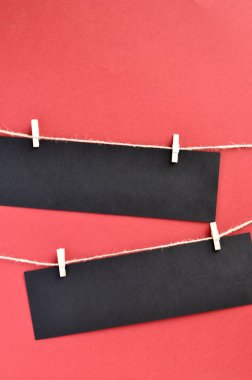 Black Friday konsepti: kırmızı bir arka plan üzerinde bir ip clothespins tarafından ekli metin için boşluk ile siyah kağıt şeritler.