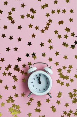 Tatil zamanı için pembe narin arka plan üzerinde beyaz çalar saat ve yıldız konfeti.