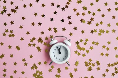 Tatil zamanı için pembe narin arka plan üzerinde beyaz çalar saat ve yıldız konfeti.