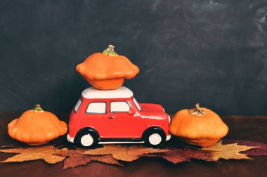 Yapraklar ve ahşap arka plan üzerinde kırmızı oyuncak araba ve turuncu kabaklar ile Sonbahar kompozisyon