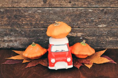 Yapraklar ve ahşap arka plan üzerinde kırmızı oyuncak araba ve turuncu kabaklar ile Sonbahar kompozisyon