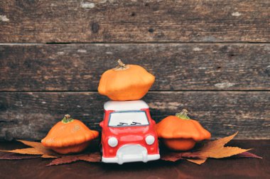 Yapraklar ve ahşap arka plan üzerinde kırmızı oyuncak araba ve turuncu kabaklar ile Sonbahar kompozisyon