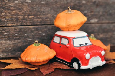 Yapraklar ve ahşap arka plan üzerinde kırmızı oyuncak araba ve turuncu kabaklar ile Sonbahar kompozisyon