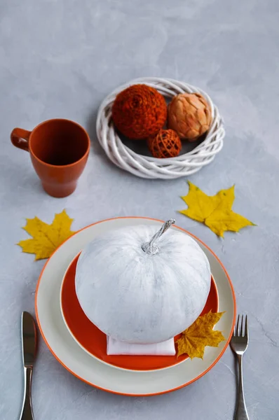 Pumpkin painted white lies on an orange plate and yellow leaves to decorate the table for thanksgiving and autumn table setting — Stock Photo, Image
