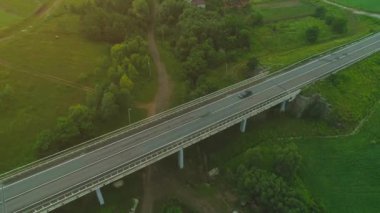 Havadan görünüm. Ormanlık çayır alanları ile çevrili pastoral tarım vadisinde doğal ülke karayolu üzerinde uçan. 4k.