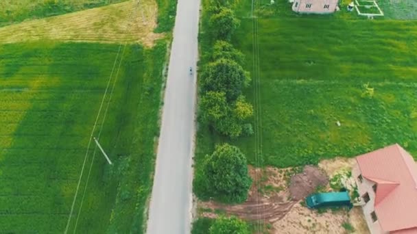 Antena Drone widok rowerzysta jazdy wzdłuż prostej drogi asfaltowej, obszar wiejski. 4K. — Wideo stockowe