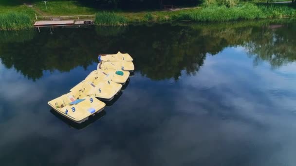 Utsikt over stille innsjø med padlebåter på, med benker til sutting på bredden. 4K . – stockvideo