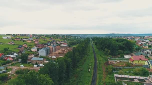 Vista aérea de los tejados de la ciudad casas residenciales parques viajero carretera y ferrocarril largo . — Vídeos de Stock