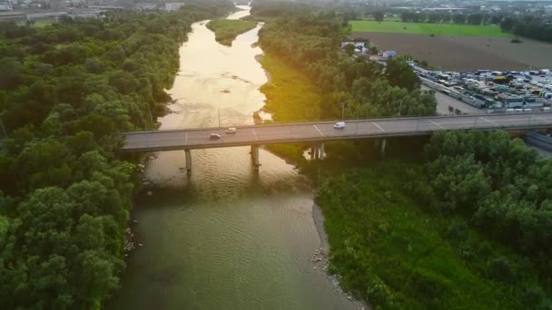 4K εναέρια κορυφή κάτω όψη των αυτοκινήτων που λείπουν το ένα το άλλο, οδηγώντας κατά μήκος της μεγάλης γέφυρας, πάνω από το ήρεμο ποτάμι πράσινο νερό. 4K. — Αρχείο Βίντεο