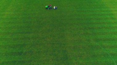 Futbol çimlerini kesen adamın evinden havadan görünümü. 4k.