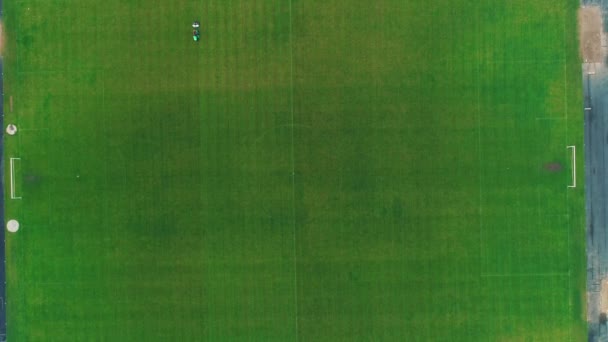 サッカー場で緑の草を刈る大きな芝刈り機の航空写真。4k. — ストック動画
