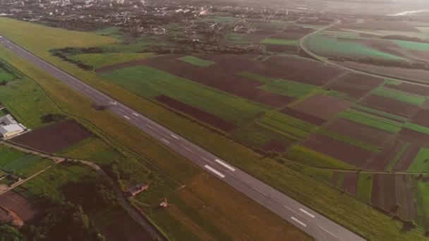 Luftaufnahme eines kleinen Flughafens mit startendem Ausreißer und weißem Flugzeug, das überfliegt. 4k. — Stockvideo