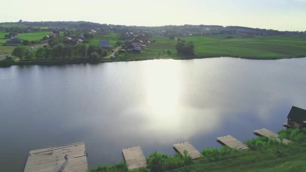 Vista aérea mãe e filha, em pé no molhe. Lago tranquilo fascina um olho. Zoom. 4K . — Vídeo de Stock