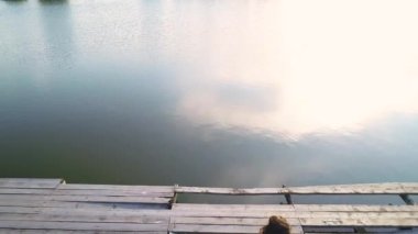 Oldukça göl yansıması havadan görünümü. Moda kız, beyaz elbiseli güvertede duruyor ve hayatın tadını çıkarıyor. 4k.